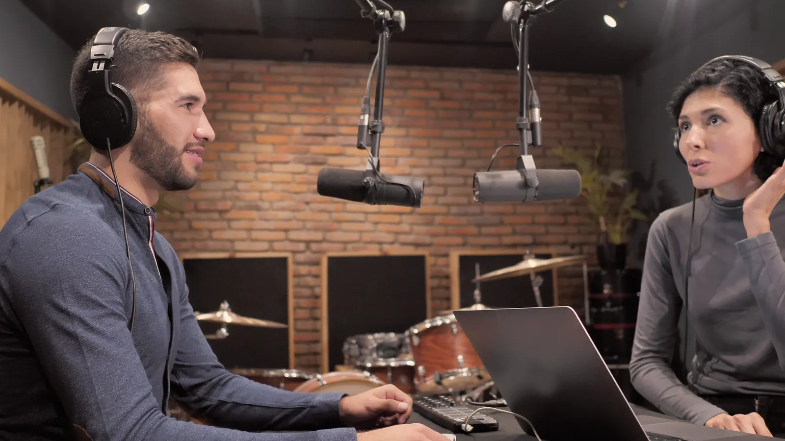 A wide shot of a podcast studio: the host on the left and the guest on the right, each face marked with a numbered box.